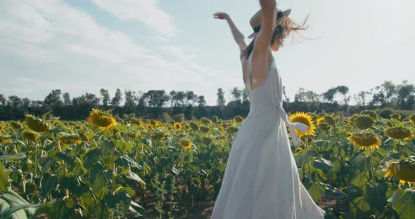 Happy Smiling Tourist Woman Dancing on Sunflower Field at Summer Vacation alt