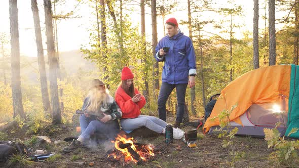 Young Friends Relax Comfortably and Drink Hot Tea on Autumn Evening in the Open Air alt