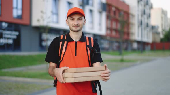 Portrait of Young Courier Delivery Man With Red Backpack Holding Pizza in Carton Boxes