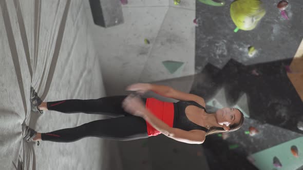 Vertical Video Portrait of a Female Climber Stands Against the Background of a Climbing Wall and Use alt