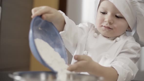 Closeup of a Child Sprinkles Flour in a Bowl for Making a Cake