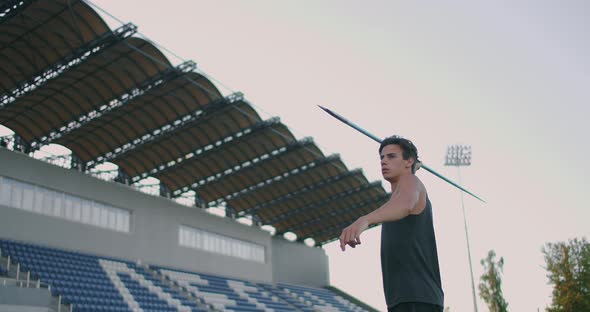 Slow-motion: a Male Athlete at the Stadium Concentrates Runs Up and Throws a Javelin. Preparation alt