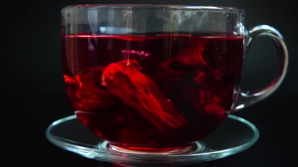 Preparation of Hibiscus tea in a glass cup. alt