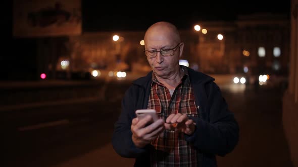 An Elderly Man with a Night on the Road Use a Smartphone alt