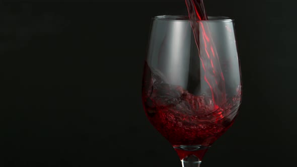 Pouring Red Wine in Super Slow Motion on Black Background alt