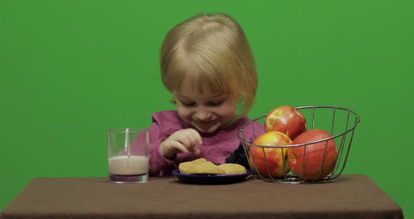 Girl Sitting at the Table and Eating Chocolate, Cookies and Drinks Cacao alt