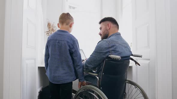 Bearded Man in Wheelchair which Talking with His Positive Smiling 8-Aged Son alt