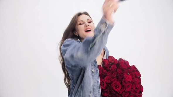 Brunette Lady with Long Hair Sniffing Bouquet of Red Roses