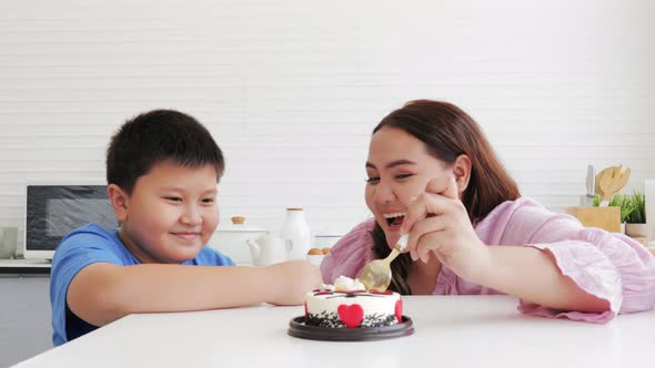 Asian Son and mother eating a cake together on Mother's day