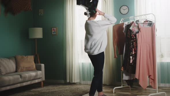 Young Girl in a White Sweater Scatters Clothes Around the Room alt