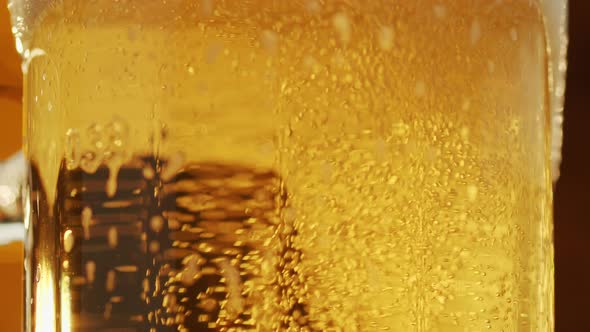 Close-up of bubbles rising in the glass of fresh beer, foam running down.