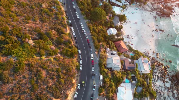 top down view of cars driving on Clifton Beach Road during sunset in Cape Town, aerial alt