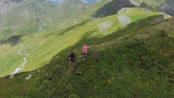 Aerial: couple backpackers hiking on mountain top Summer adventures on the Alps alt