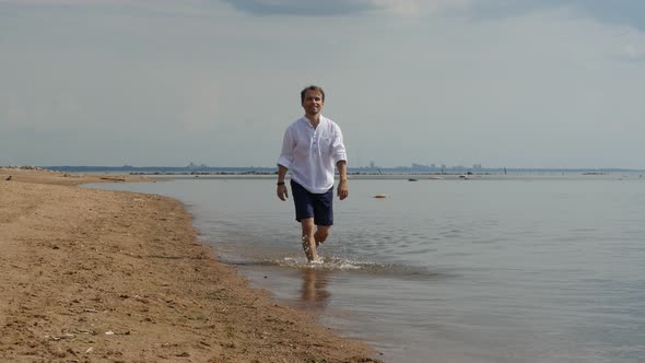 Happy Man Walking Along the Sandy Beach