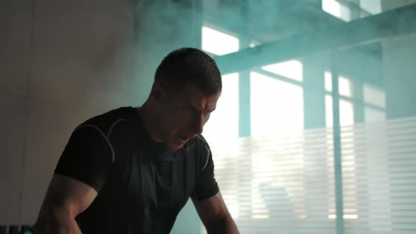 Caucasian Male Hardly Working Out with Heavy Dumbbells in Smoked Gym alt