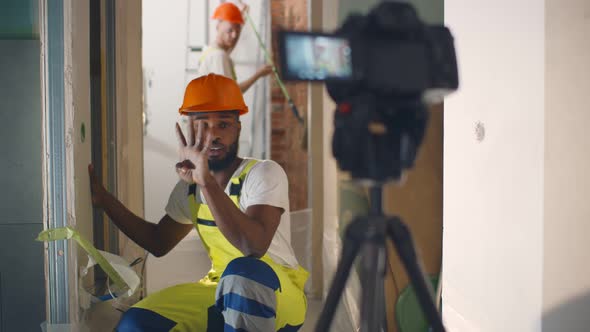 Portrait of African Renovation Worker Filming Video About Wall Construction on Camera alt