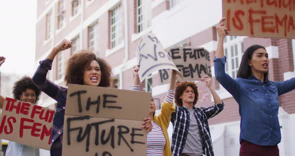Diverse group of men and women holding placards raising fists shouting during protest alt