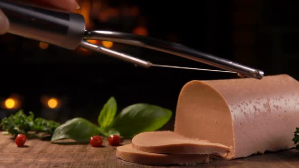 A Special String Knife Is Cutting Delicious French Foie Gras on a Wooden Board alt