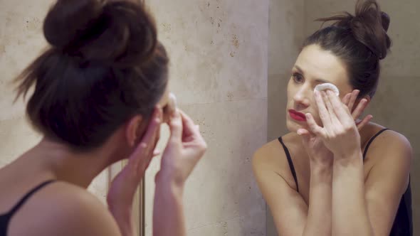 Beautiful Young Woman Doing Makeup Removal in the Mirror  alt