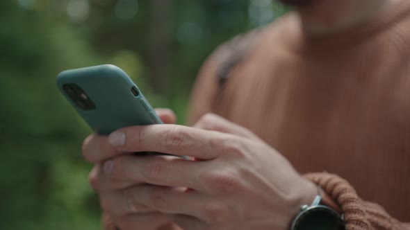 A Man Walks in the Woods and Writes a Message on His Mobile Phone alt