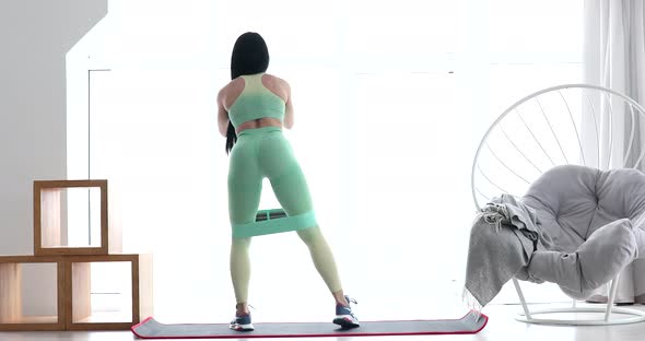 Athletic muscular girl sportswoman does exercise for buttocks with loop band. Healthy lifestyle.