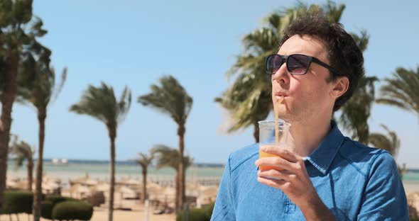 Man on Vacation Backdrop of Palm Trees Sea Drinks Orange Cocktail Enjoying Summer Holiday at alt