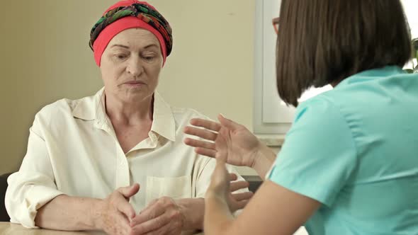 Cancer Female Patient Wearing a Headscarf After Chemotherapy Consults with an Oncologist
