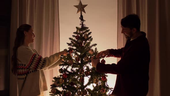 Happy Couple Decorating Christmas Tree at Home