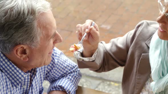 Senior woman feeding sweet food to senior man in cafe 4k alt