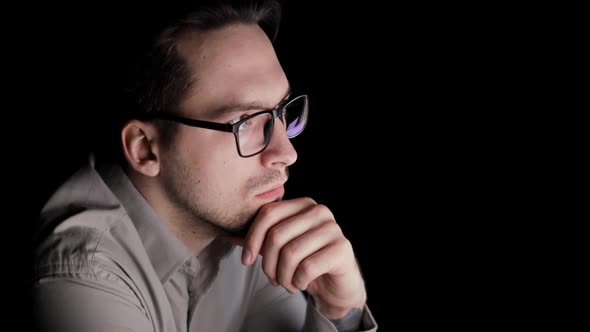 Man Is Looking at Screen in the Dark and Thinking Sitting in Workplace alt