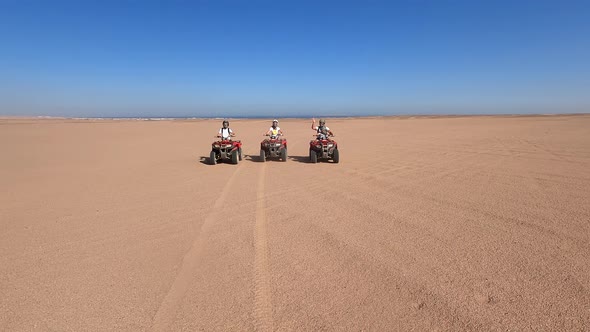 A Happy Family is Having Fun During the Summer Holidays on Quad Bikes in the Desert