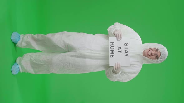 Full Body Of Asian Man Wear Uniform Ppe And Holding Stay At Home Sign In Green Screen Studio alt