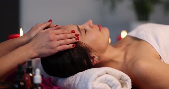 Young Woman Enjoying Head and Face Massage at Spa alt