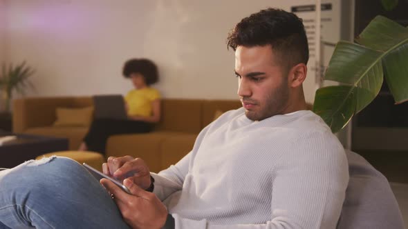 Mixed race man on smartphone in creative office alt