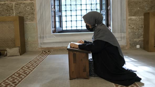 Reading Holly Book to Allah Masked Muslim Woman Reading Quran in Historical Mosque alt