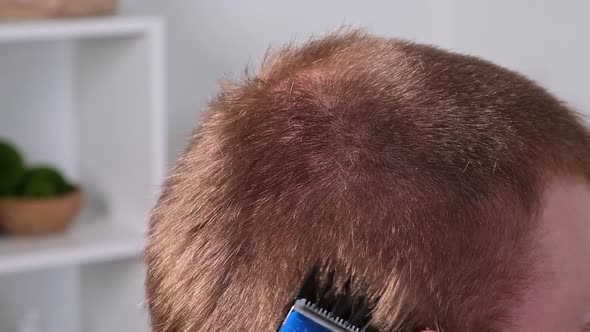 A Man Cuts His Hair with Clipper