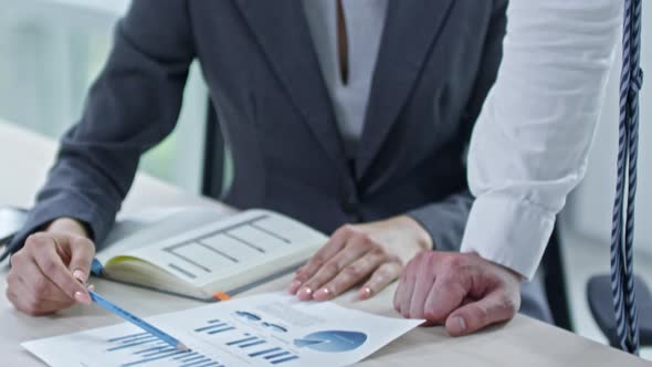 Businesswoman and Businessman Discussing Financial Graphs alt