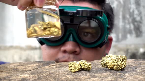 Asian man looking pure gold minerals found in mines in the bottle