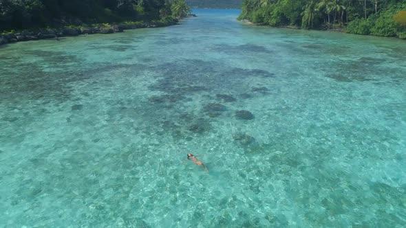 A woman swimming in a tropical green lagoon in Bora Bora tropical island alt