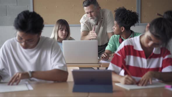 Professor Assisting Multiethnic Students in Modern Secondary School Classroom alt