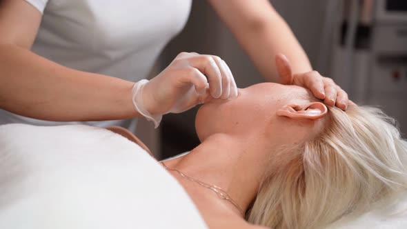 Woman masseur makes face relaxing massage to young beautiful female client blonde and spa treatment alt