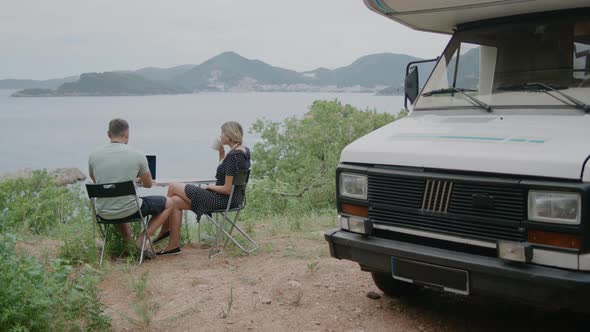 Young  travel couple sitting near motor home RV campervan. alt