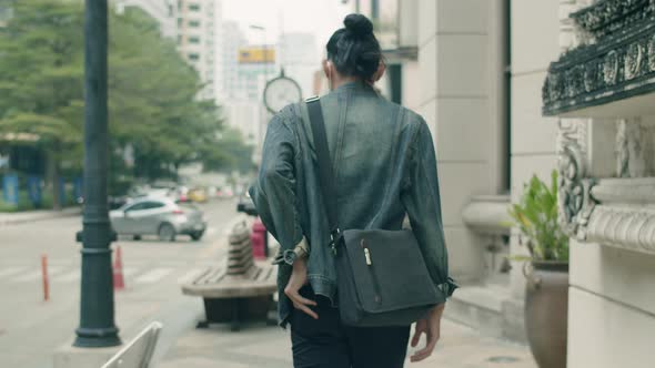 Handsome Asian man wearing a mask walking on the street and looking aside around the city.