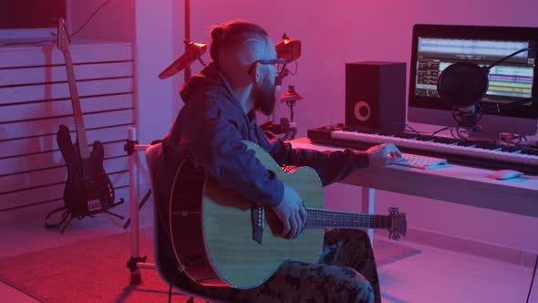 Concept of Hobby and Making Music. Young Bearded Man Plays the Guitar in a Home Music Studio alt