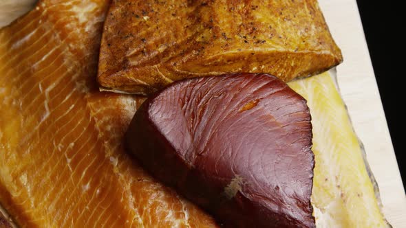 Rotating shot of a variety of delicious, premium smoked meats on a wooden cutting board alt