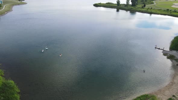 Drone view of recreational lake with paddle boards. Walking path winding around the edges.