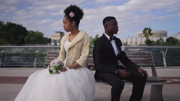 Sad Argued Couple Sitting Back to Back on Bench As Bride Leaving Wedding Bouquet and Walking Away in alt