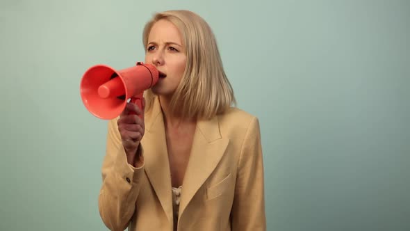 Beautiful woman in jacket with megaphone on blue background alt