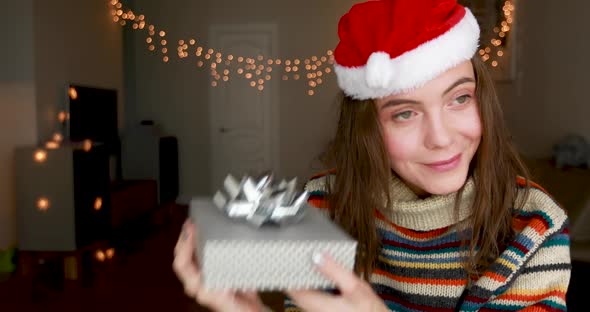 Young Woman Opens Gift Box with Interest and Looks Inside alt