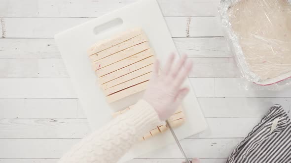 Flat lay. Step by step. Cutting homemade candy cane fudge on a white cutting board. alt